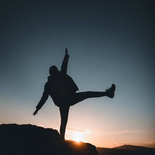 Silhouette of a person in a balancing athletic pose during sunrise.